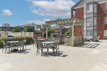 a patio with tables and chairs outside of a building at The Pointe at St. Joseph Apartments, South Bend, IN, 46617